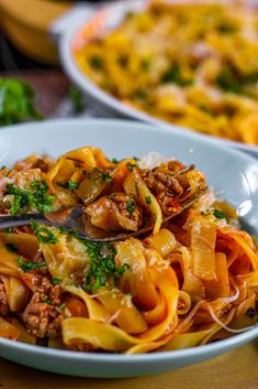 a bowl of pasta with meat and parsley on the side next to other dishes