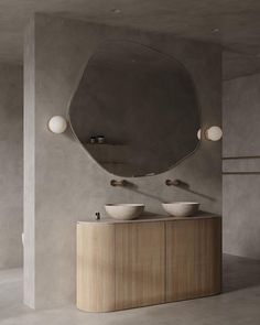 a bathroom with two sinks and a large round mirror on the wall over it's counter