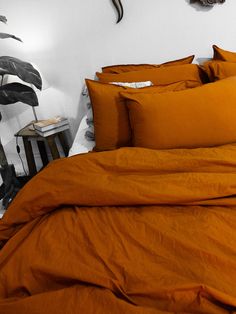 a bed with orange sheets and pillows in front of a wall mounted antelope