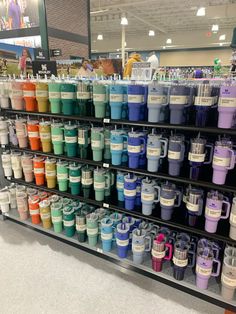 there are many different colored cups on the shelf in this store, and one is full of them