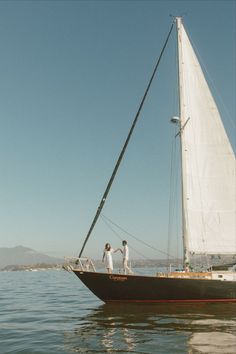 two men standing on the deck of a sailboat