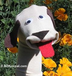 a stuffed dog has its tongue out in front of yellow flowers