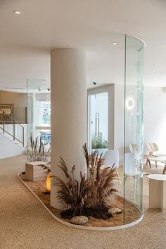 an empty room with glass walls and plants in the center, surrounded by white tables and chairs