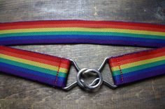 a rainbow colored belt with a metal buckle on it's end, sitting on top of a wooden table