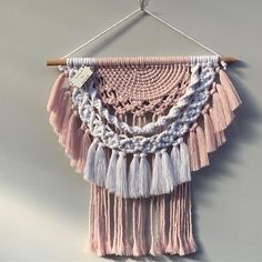 a pink and white wall hanging with tassels