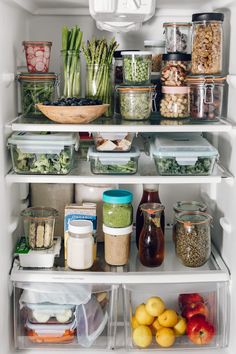 an open refrigerator filled with lots of food and containers full of vegetables, fruits and veggies