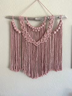 pink crocheted wall hanging on a white wall