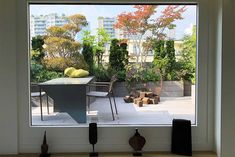 an open window shows the back yard and patio with modern furniture in it, as well as potted trees