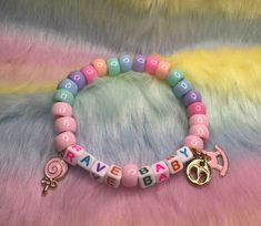 a close up of a bracelet with beads and charms on a fur background, that says happy birthday