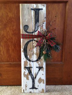 a wooden sign with the letter j on it and a bow hanging from it's side