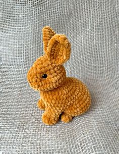 a crocheted stuffed animal sitting on top of a white cloth covered tablecloth