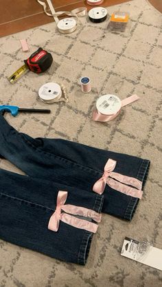 sewing supplies are laid out on the floor next to jeans and other crafting items