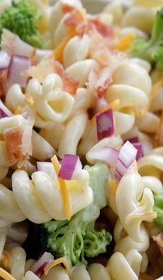 pasta salad with broccoli, red onions and cheese in a white bowl on a table