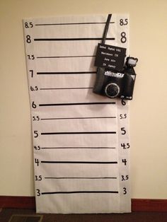 a towel with a camera hanging on it's side next to a ruler that is taped to the wall