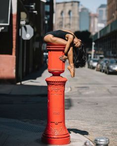 a woman leaning on top of a red fire hydrant