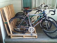 two bikes parked next to each other in front of a house with wooden crates on the porch