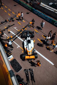 an aerial view of a race car being worked on by some people in the background