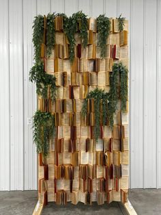 a book sculpture made out of books with plants growing on them and attached to the wall
