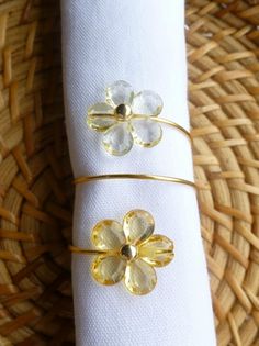 two napkin rings with flowers on them sitting on a woven place mat next to a wicker basket