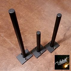 three black metal poles on top of a wooden floor