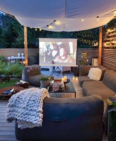 an outdoor living area with couches and a projector screen in the middle of it