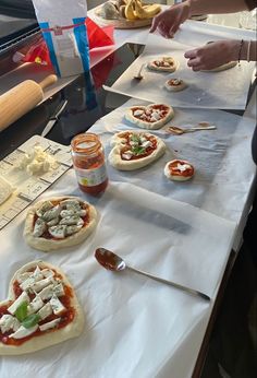 several small pizzas sitting on top of a white table covered in cheese and sauce