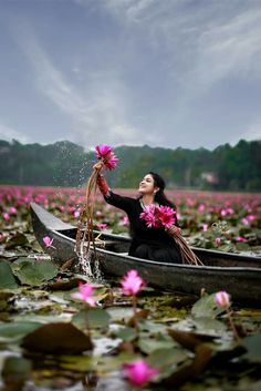 a woman in a canoe with pink flowers floating on the water and splashing from her hands