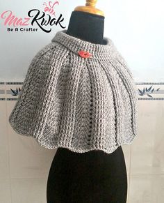 a mannequin wearing a gray knitted shawl on top of a table