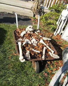 a wheelbarrow filled with skeletons and bones sitting in the grass next to a house