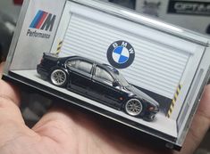 a small black car is on display in front of a bmw garage door with the logo m performance