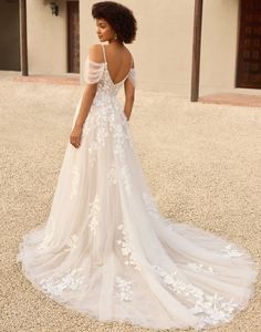 a woman in a white wedding dress standing on the ground with her back to the camera