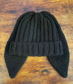 a black knitted beanie hat on top of a wooden table