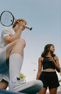 a man holding a tennis racquet standing next to a woman