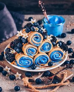 blueberry rolls are arranged on a plate with berries around them and some chocolate chips in the background