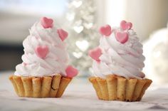 two cupcakes topped with white frosting and pink hearts