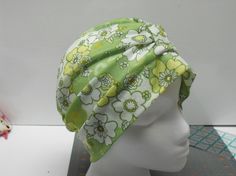 a white mannequin head wearing a green and yellow flowered turban