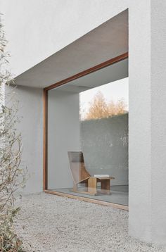 an empty chair sitting in the middle of a room next to a wall with glass doors