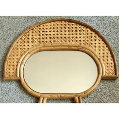 an oval bamboo mirror on top of a wooden stand next to a carpeted floor