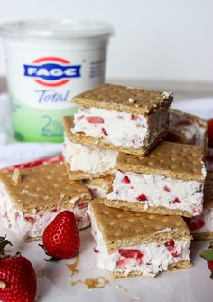 strawberry shortbread ice cream sandwiches stacked on top of each other with strawberries and yogurt in the background