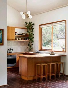 a kitchen with wooden cabinets and tile flooring next to a window that has potted plants on it