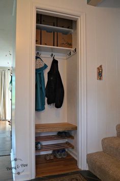 an open closet with two coats hanging on the wall and shoes sitting on the floor