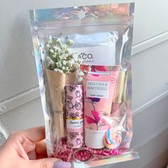 a person holding up a package with various items in it's packaging and flowers