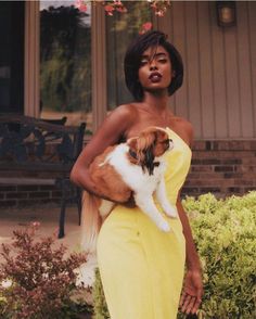 a woman in a yellow dress holding a dog