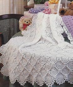 there is a crocheted blanket and teddy bears on the table