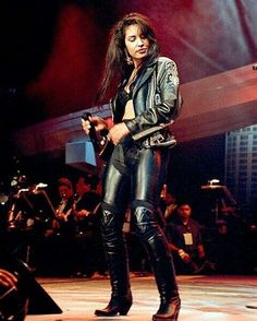 a woman in black leather pants and boots on stage