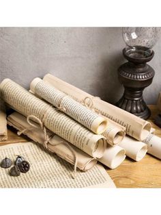 four rolled up books sitting on top of a wooden table next to an open book