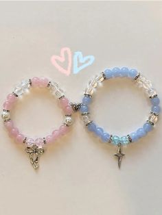 two bracelets with charms on them sitting next to each other and one has a star charm