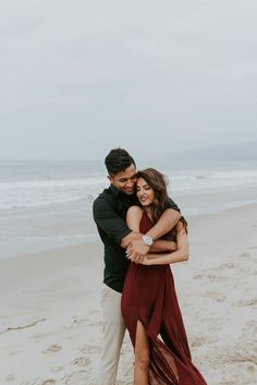 an engaged couple hugging on the beach