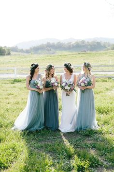 four bridesmaids laughing together in the grass with their bouquets around their necks