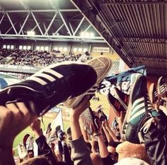 people are holding their feet up in the air at a baseball game, with fans watching